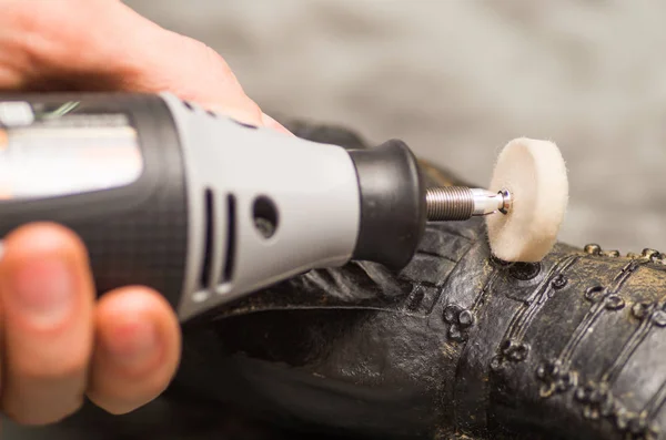 Close-up van een selectieve aandacht van een hardworker man met een polijstmachine via een metalen standbeeld in een vage grijze achtergrond — Stockfoto