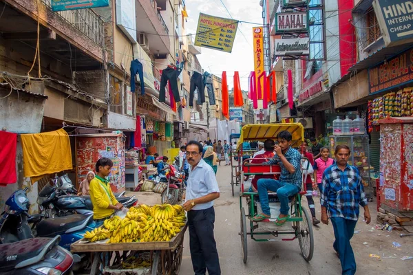 Delhi, Indie - 25 września 2017: Niezidentyfikowanych ludzi chodzących w ruchliwej ulicy, z młodym mężczyzną w koszyku z bananów w Paharganj Delhi z muzułmańskich kupujących — Zdjęcie stockowe