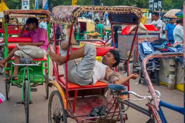 Delhi, indien - 25. september 2017: ein unbekannter mann ruht sich auf den straßen in paharganj, delhii über seinen roten rikschas aus. delhi ist die zweitbevölkerungsreichste stadt indiens nach mumbai — Stockfoto