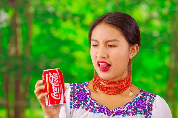 Quito, Ecuador - 06 maggio 2017: Bella giovane donna indigena che beve una coca cola e si fa una brutta faccia su uno sfondo forestale — Foto Stock