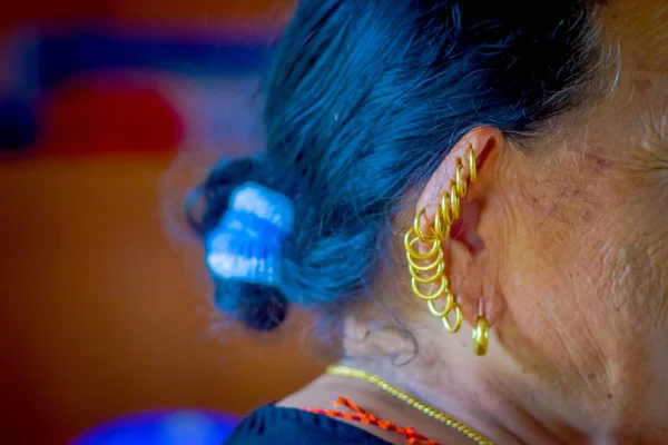 POKHARA, NEPAL - NOVEMBER 04, 2017: Close up of many earrings in the ear of old woman posing for camera in Pokhara, Nepal, in a blurred background — Stock Photo, Image