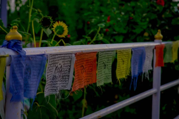 POKHARA, NEPAL, SEPTEMBER 04, 2017: Close up of colorful fabrics with a description, with a beautiful brilliant-white World Peace Pagoda behind, in Pokhara is a massive Buddhist stupa, fish eye effect — Stock Photo, Image