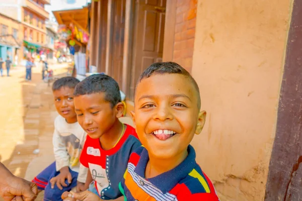 BHAKTAPUR, NEPAL - 04 NOVEMBRE 2017 : Gros plan d'un groupe d'enfants regardant la caméra et un garçon souriant, à l'extérieur sur la place entourant les bâtiments anciens et rustiques à proximité des marchés situés dans — Photo