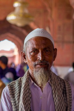 Delhi, Hindistan - 27 Eylül 2017: Kamera arka plan bulanık Jama Mescidi Camii Delhi, Hindistan tapınakta içinde bakarak beyaz sakalı ile beyaz bir Hint şapka giyen bir adam portresi