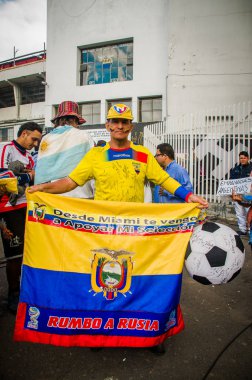 Quito, Ekvator - 11 Ekim 2017: Ekvador, sarı, mavi ve kırmızı ve giyen renklerle boyalı yüzü ile sarı bir şapka giymiş bir Eduadorian bayrağı onun elinde tutan bir adamın kapat