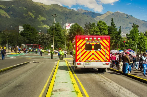 QUITO, ECUADOR - 23 DE OCTUBRE DE 2017: Personas no identificadas caminando por las calles con una ambulancia estacionada en la calle durante el desfile de las Fiestas de Quito —  Fotos de Stock