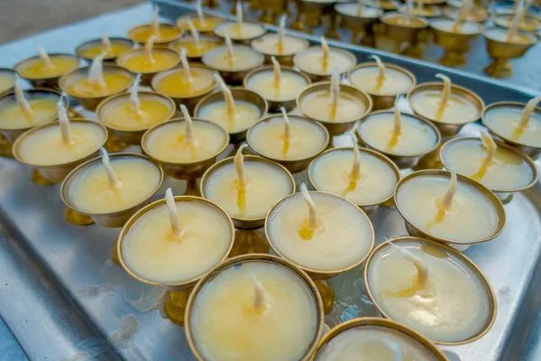 Close up of candels inside of a golden goblets over ametallic tray in a table with a view of Boudhanath Stupa building at outdoors in Kathmandu, Nepal — Stock Photo, Image