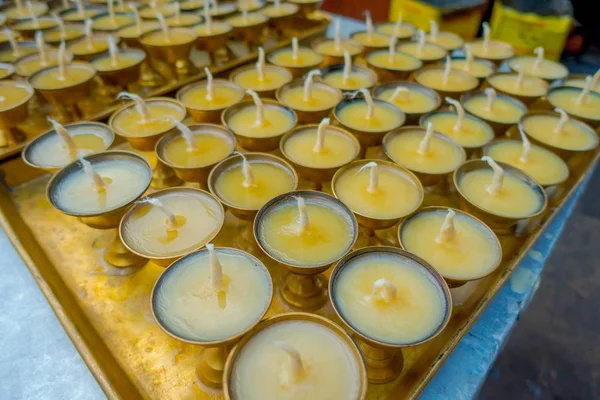 Zbliżenie na świeczki wewnątrz złote puchary nad ametallic taca w tabeli z widokiem stupy Boudhanath na zewnątrz budynku w Kathmandu, Nepal — Zdjęcie stockowe