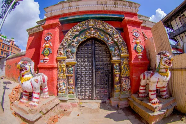 KATHMANDU, NEPAL 15 OCTOBRE 2017 : Gros plan de deux gardiens lapidés et l'entrée d'un temple, avec une structure sculptée dans la porte et le cadre de l'entrée du bâtiment, en reconstruction après — Photo