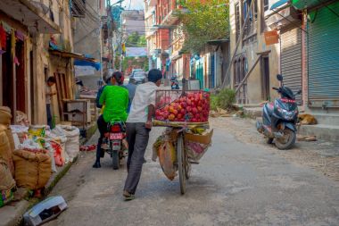 Katmandu, Nepal 15 Ekim 2017: Bir bisiklet bir metal sepet ve motorcicles tarihi merkezi Katmandu, Nepal sokakta insanlar içinde bazı elma meyve ile tanımlanamayan erkekte