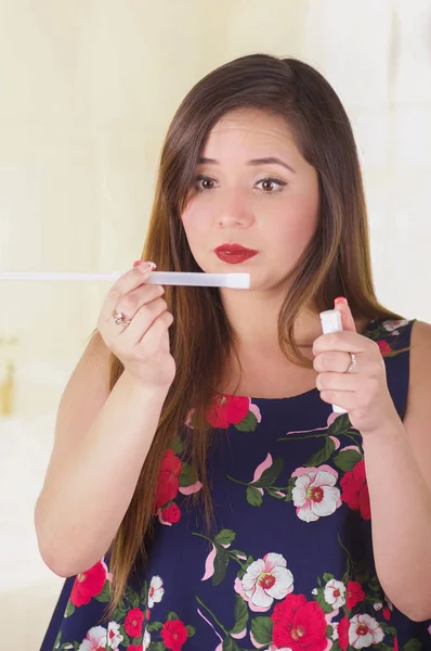 Acercamiento de una joven sorprendida sosteniendo en sus manos un objeto médico y crema utilizados para la medicina de la infección vaginal, en un fondo borroso — Foto de Stock