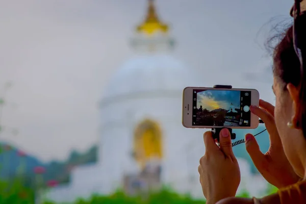 Ποκάρα, Νεπάλ, 04 Σεπτεμβρίου 2017: Κοντινό πλάνο του μια όμορφη θέα του ναού στην οθόνη ενός smartphone με θολή φόντο λευκό λαμπρό κόσμο ειρήνη παγόδα πίσω, σε Ποκάρα είναι ένα — Φωτογραφία Αρχείου