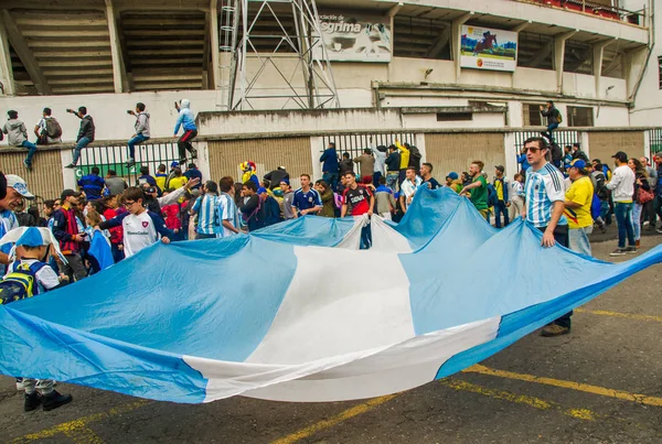 QUITO, ECUADOR - 11 OTTOBRE 2017: Primo piano dei tifosi argentini con una bandiera argentina che indossano la sua maglia da calcio ufficiale e sostengono la sua squadra all'aperto, urlando e saltando — Foto Stock