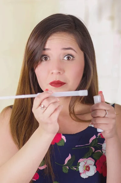 Close up of a surprised young woman holding in her hands a medical object and cream used for vaginal infection medicine, in a blurred background — Stock Photo, Image