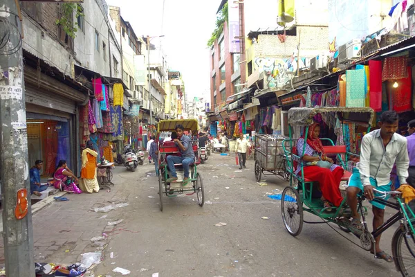 Δελχί, Ινδία - 25 Σεπτεμβρίου 2017: Αγνώστων ανθρώπους που περπατούν σε ένα βρώμικο δρόμο στην περιοχή Paharganj, Δελχί με Rickshaws και ένα auto-rickshaws. Το Δελχί είναι η δεύτερη πιο πυκνοκατοικημένη πόλη στην Ινδία μετά Mumbai — Φωτογραφία Αρχείου