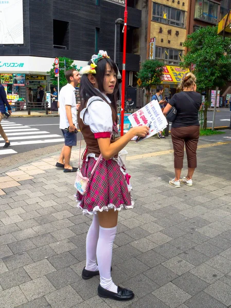 Tokyo, Japan juni 28-2017: onbekende vrouw holsing in haar handen en informatieve vliegers beroemde rode lichten district, Kabukicho, omgeving van grote gebouwen en reclame, gevestigd in Tokio — Stockfoto