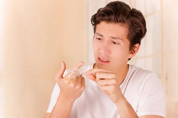 Porträtt av orolig man hålla en öppen bruten kondom med ena handen framför ansiktet och att vidröra den trasiga bit med sin andra hand, ett tecken på sex sjukdom, i en suddig bakgrund — Stockfoto