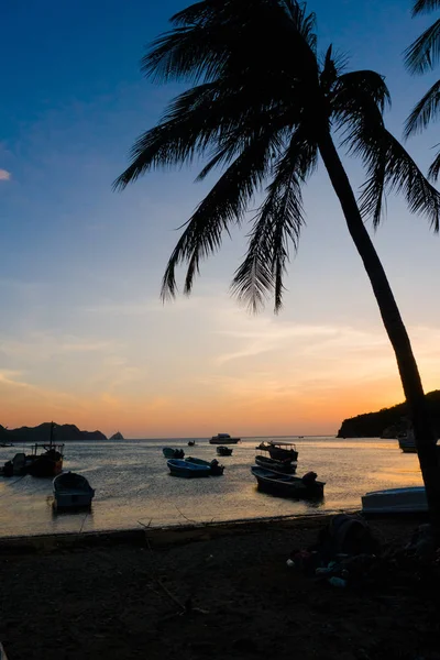 SANTA MARTA, COLOMBIA - OCTOBER 10, 2017: Beautiful sunset in a caribean beach with a shadow of palm trees and boats in the water in Taganga, Colombia — Stock Photo, Image