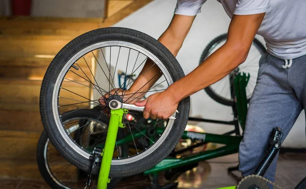 Close up of bicycle mechanic in a workshop in the repair process of the wheel with a wrench