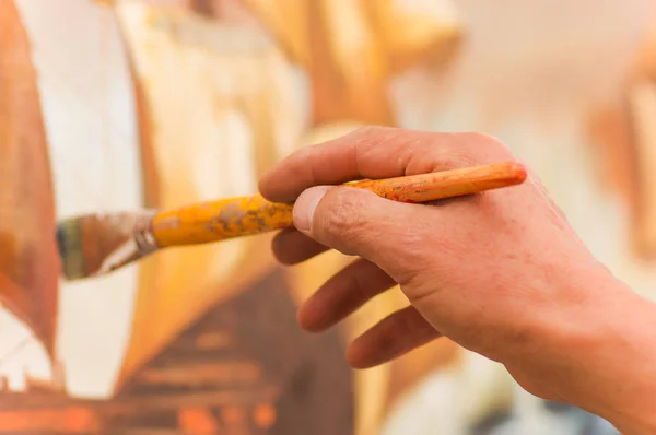 Detail člověka ruku husing štětečkem nad barevnou paletu v ateliéru, v rozmazané pozadí — Stock fotografie