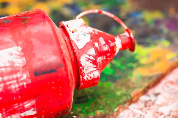 Крупный план кистей краски красным пластиковым цветом над цветовой палитрой в студии, на размытом фоне — стоковое фото