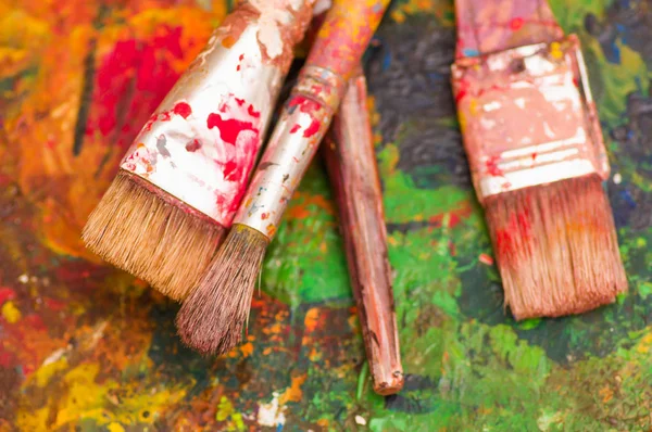 Top view of paint brushes over a color palette in a blurred background — Stock Photo, Image