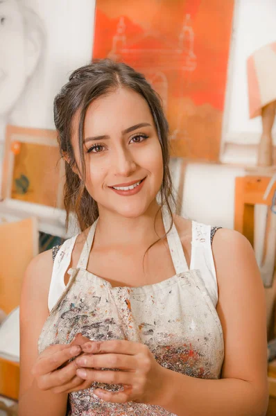 Gros plan de belle femme céramiste regardant la caméra et travaillant sur la sculpture sur table en bois dans l'atelier — Photo