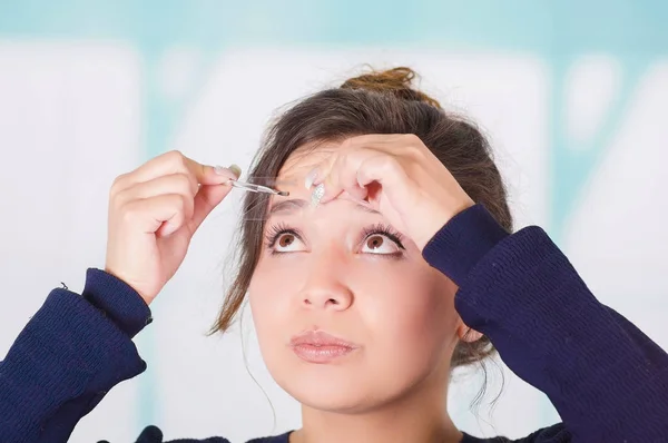 Primer plano de la joven hermosa mujer haciendo un lío en su ceja en un fondo borroso — Foto de Stock