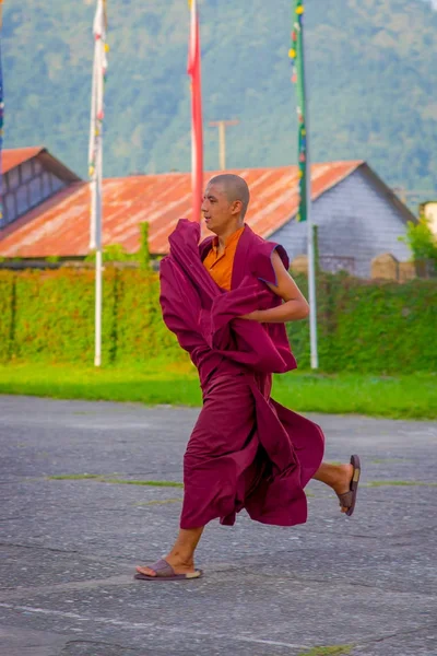 POKHARA, NEPAL - 06 DE OCTUBRE DE 2017: Adolescente monje budista no identificado jugando sobre un suelo apedreado al aire libre en el asentamiento de refugiados Tashi en Pokhara, Nepal — Foto de Stock