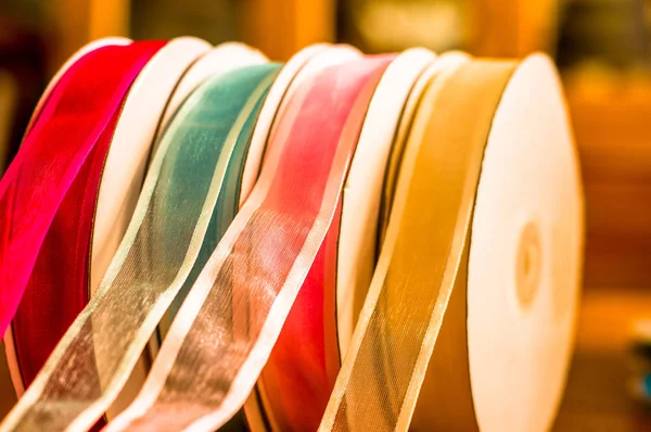 Zbliżenie rolki kolorowe tkaniny taśmy, na drewnianym stole w rozmytym tle — Zdjęcie stockowe