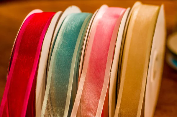 Крупным планом из рулонов разноцветной тканной ленты, на деревянном столе на размытом фоне — стоковое фото