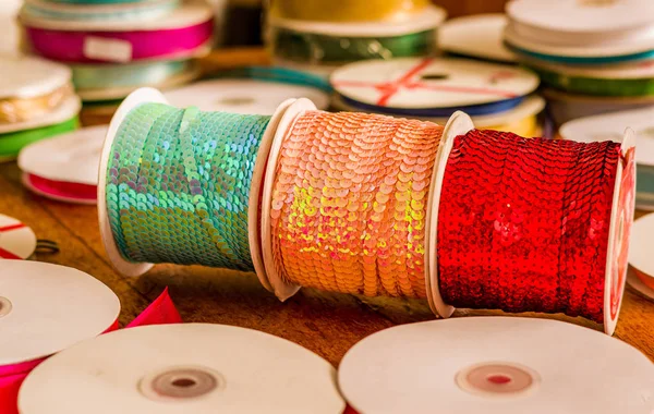 Cose up de rouleaux brillants de paillettes colorées ruban vert, rose et rouge, multicolore sur une table en bois dans un fond flou — Photo