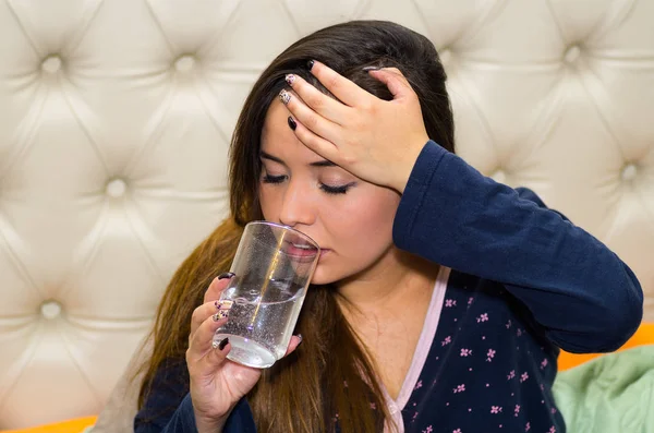 Donna ubriaca che beve un bicchiere d'acqua nel letto dopo una festa, concetto di sbornia — Foto Stock