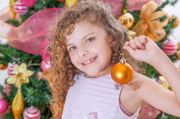 Ritratto di ragazza felice che tiene un ballo di Natale davanti a un albero di Natale, concetto di Natale — Foto Stock