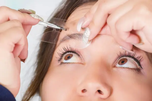 Close up van jonge mooie vrouw doen een puinhoop in haar wenkbrauw in een onscherpe achtergrond — Stockfoto