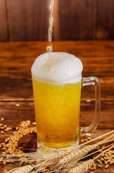 在一个模糊的背景下, 在一张木桌上的小麦树枝和小麦的泡沫, 一杯淡啤酒关闭 — 图库照片