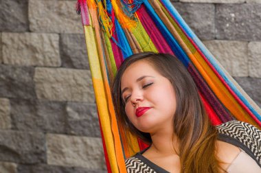 Genç kadın arka plan bulanık bahçesinde bir hamakta kestiriyor