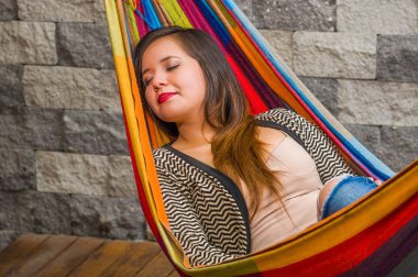 Genç kadın arka plan bulanık bahçesinde bir hamakta kestiriyor