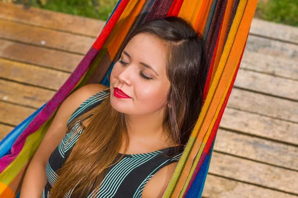 Über der Ansicht einer jungen Frau, die in einer Hängematte im Garten ein Nickerchen macht, vor verschwommenem Hintergrund — Stockfoto