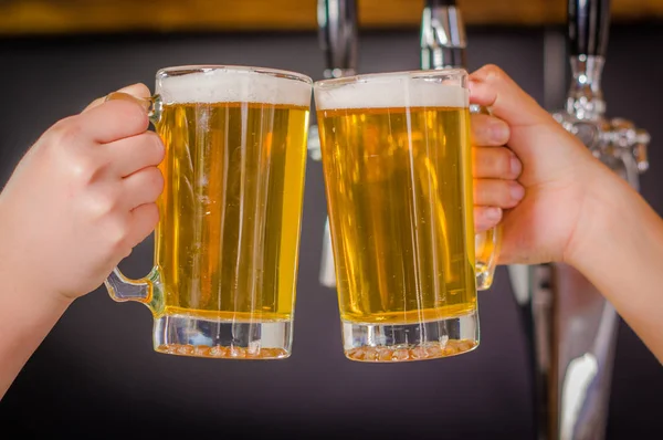 Close up van een twee vrienden juichen met glazen bier voor bier kraan gieten in een restaurant of café, in een onscherpe achtergrond — Stockfoto