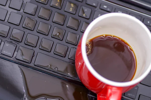 Acima da vista da gota de café e uma xícara vermelha de café sobre o laptop, danos líquido molhado e derramamento no teclado, conceito de acidente — Fotografia de Stock