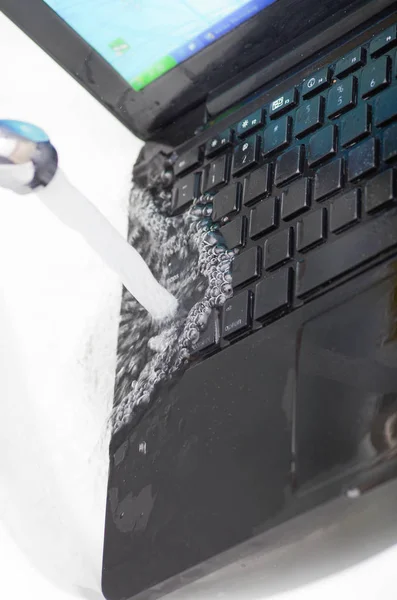 Vista acima do laptop na pia usando água para limpar o teclado — Fotografia de Stock