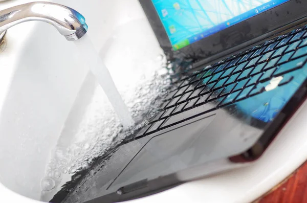Gros plan de l'ordinateur portable dans l'évier en utilisant de l'eau pour nettoyer le clavier — Photo