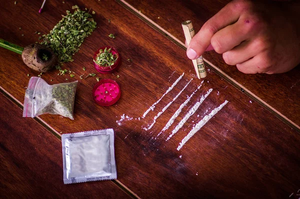 Ovanför vyn av diverse droger över ett träbord med pengar insvept, kondom och en man missbrukare beredda att använda droger, över ett träbord — Stockfoto