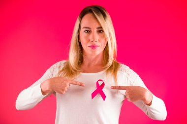 Bir pembe Meme Kanseri Bilinçlendirme şerit elleri, sağlık ve tıp kavramı bir pembe işaret eden beyaz bir bluz giyen güzel bir kadının yakın çekim