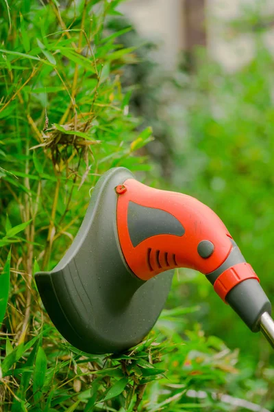 Nahaufnahme eines Rasentrimmer-Rasenmähers, der Gras mäht, über einem Grashintergrund — Stockfoto