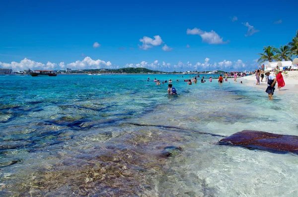 JOHNNY CAY, COLOMBIA - 21 DE OCTUBRE DE 2017: Personas no identificadas caminando por la playa y disfrutando del hermoso día soleado y nadando en el agua en la costa de la isla Johnny Cay con algunas banderas —  Fotos de Stock