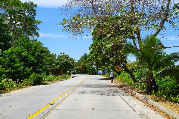 Persone non identificate che camminano in una strada di pevement a San Andres, Colombia in un bellissimo sfondo di spiaggia — Foto Stock