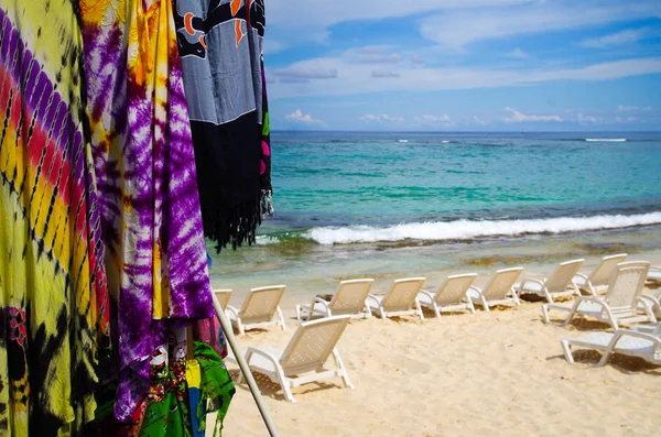 Close up of some colorful fabrics and some white plastic chairs in the sand in San Andres beach, Colombia — Stock Photo, Image