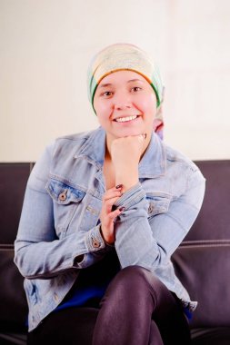 Kanserli başörtüsü, pozitif tutum, çenesini kapalı orada elinde arka plan bulanık poz siyah bir kanepede oturuyor olması giyen bir kadın yakın çekim